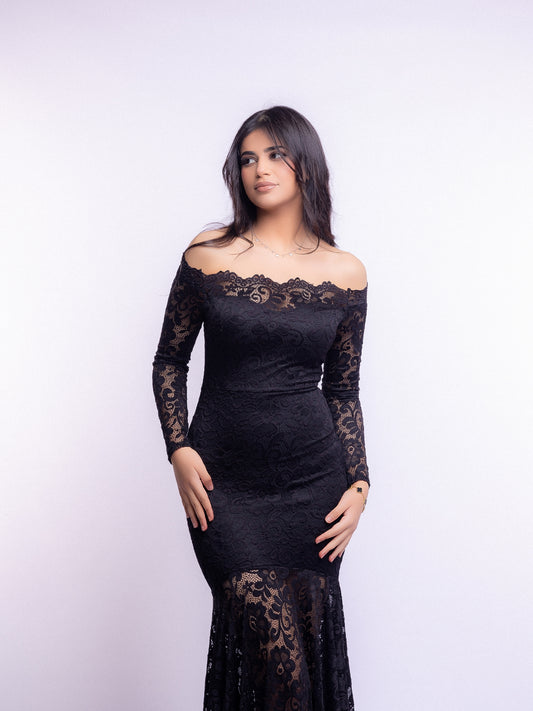 Woman wearing a black lace dress against a white background