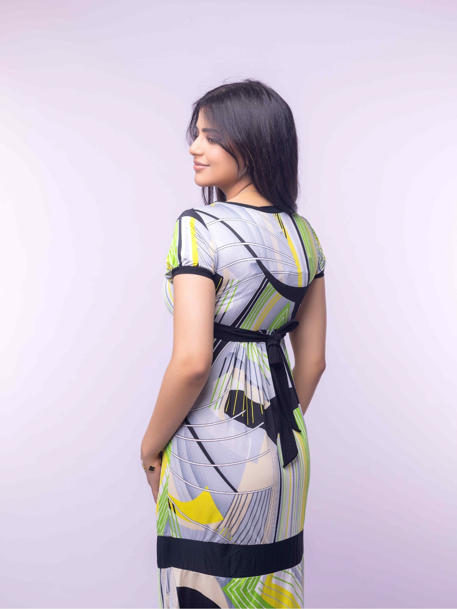 Woman wearing a colorful dress with abstract patterns on a light purple background