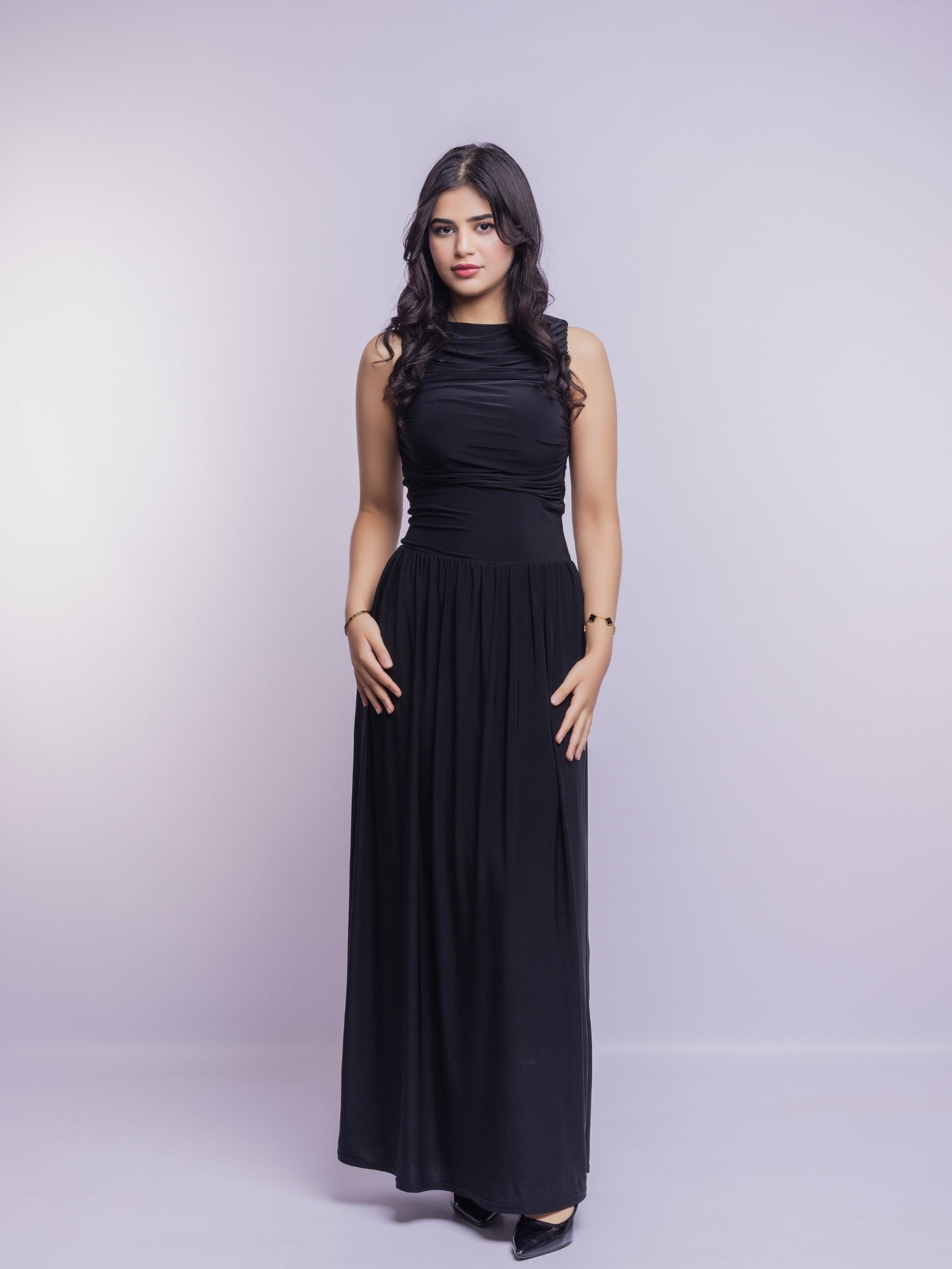 Woman wearing a black sleeveless dress against a light gray background
