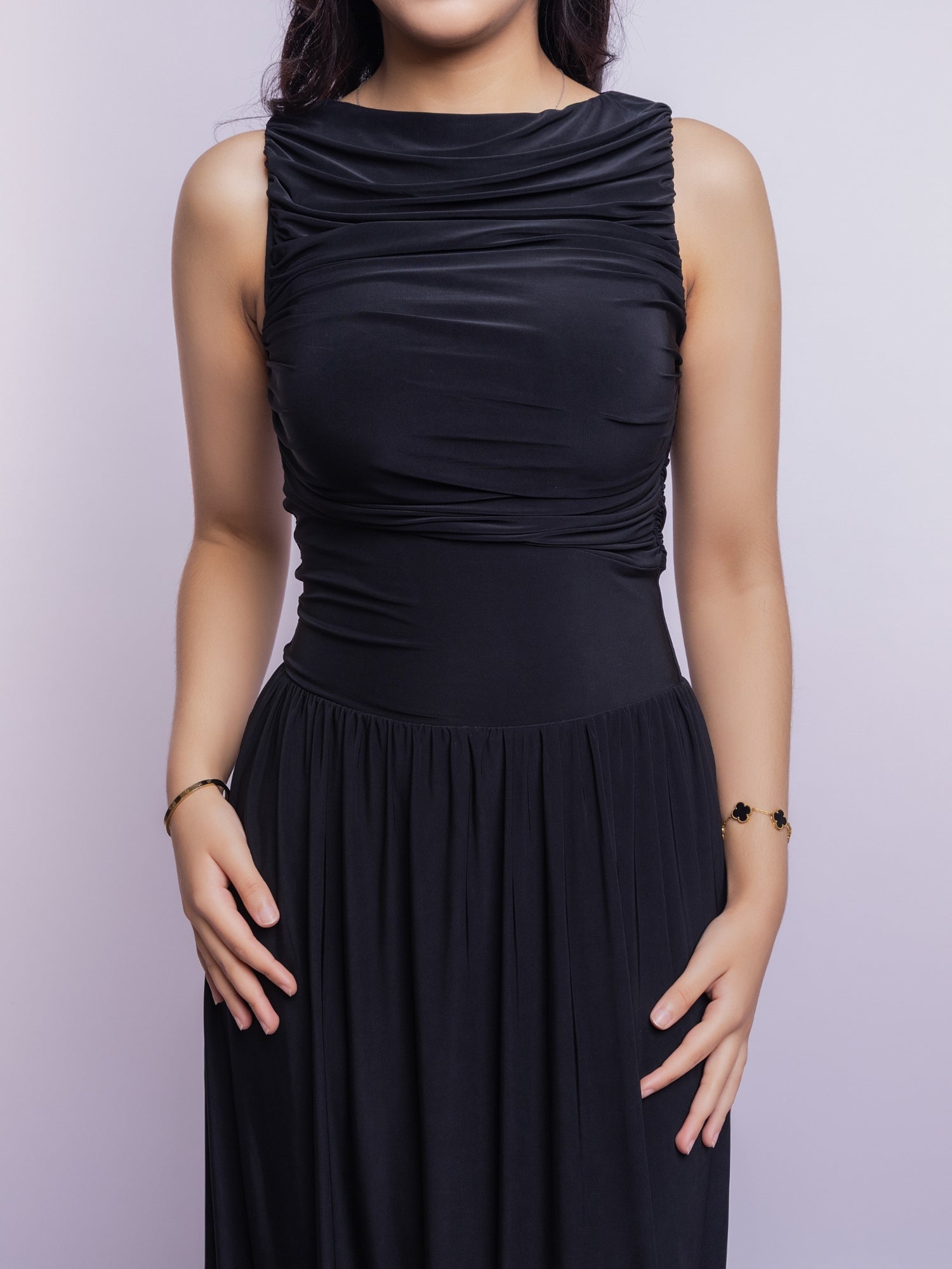 Black sleeveless dress worn by a person on a light purple background
