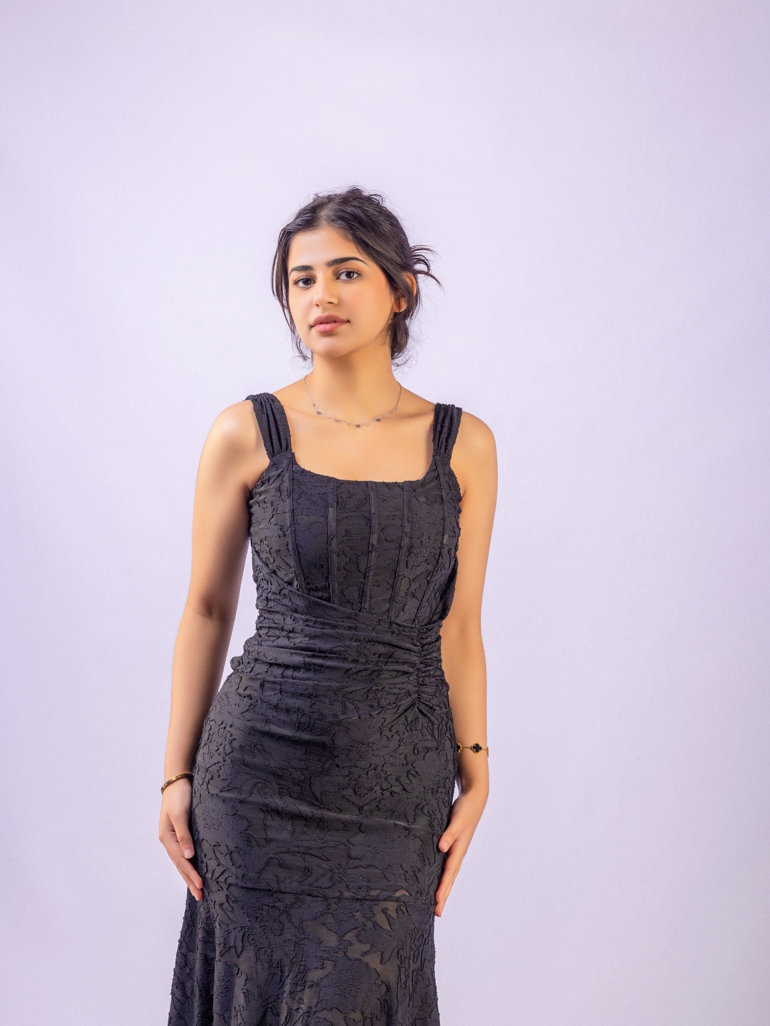 Woman wearing a black lace dress against a light purple background