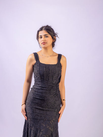 Woman wearing a black lace dress against a light purple background