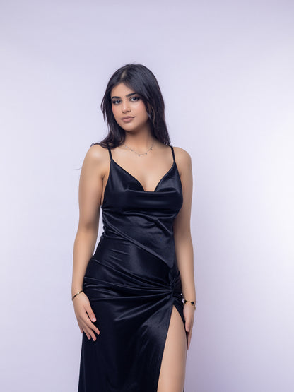 Woman wearing a black satin dress with a slit on a light purple background