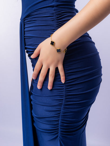 Person wearing a blue dress with a close-up of a hand and bracelet on a light purple background