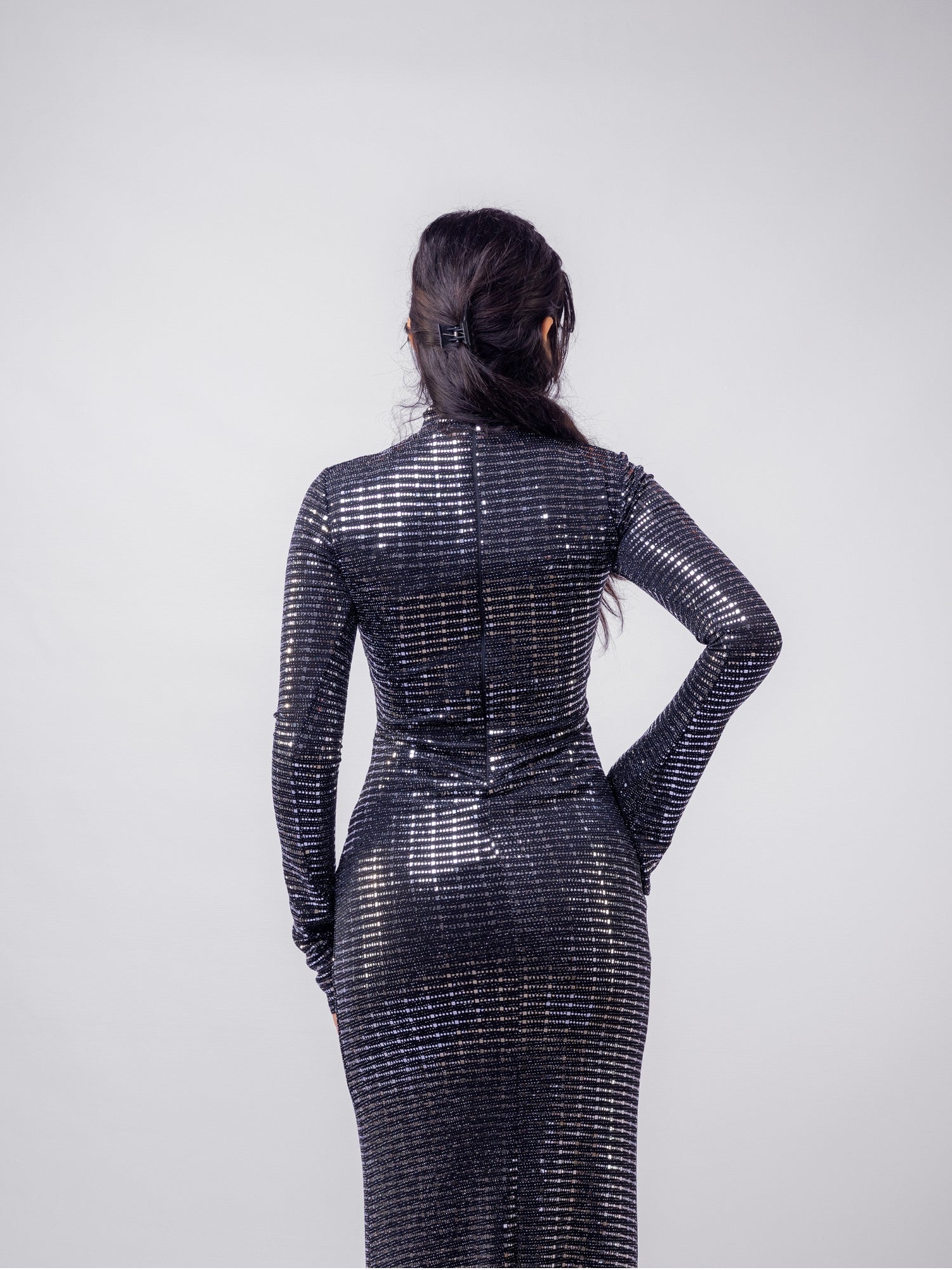 Person wearing a black sequin dress against a white background