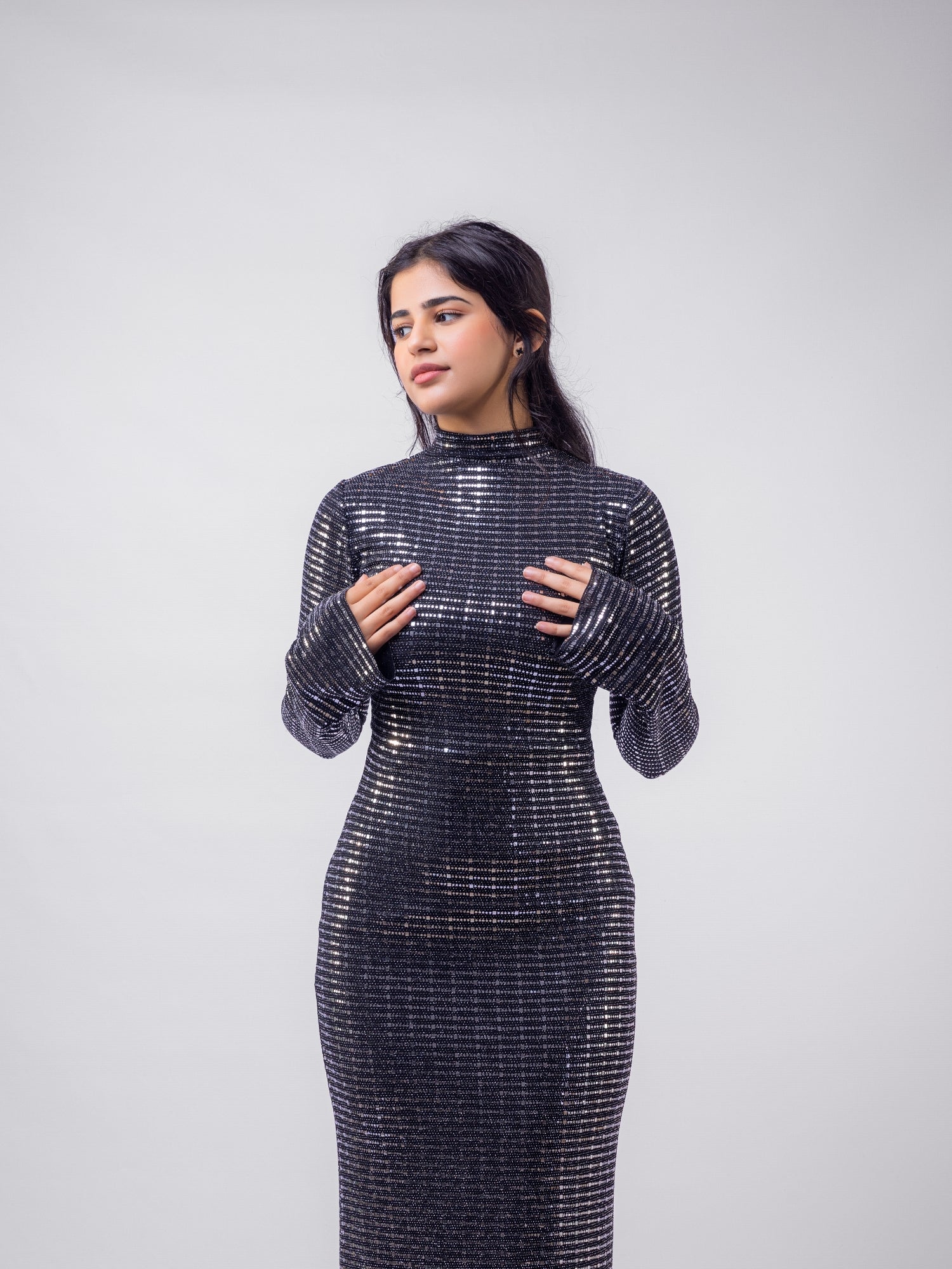 Woman wearing a sparkly black dress against a plain background