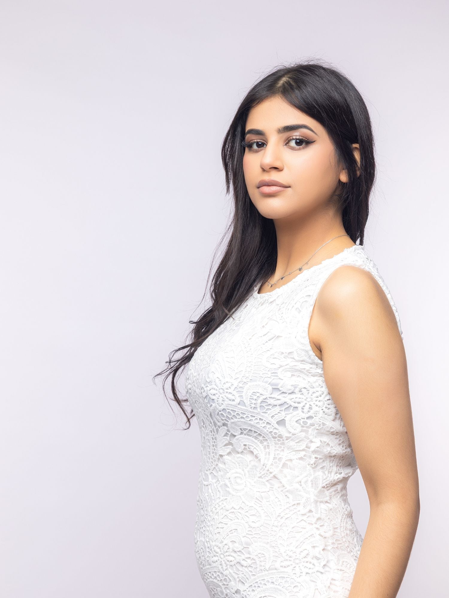 Woman wearing a white sleeveless top against a light gray background